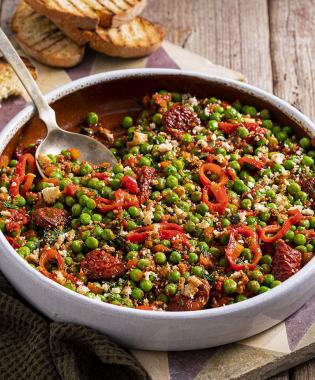 Peas in a clay pot with sun-dried tomatoes and spicy peppers